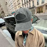 Gorra tipo baseball color negro con efecto lavado, presenta un parche ovalado bordado con la palabra Nude y detalles de desgaste en la visera.