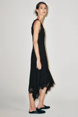 Vestido midi negro confeccionado en encaje de algodón, con escote en pico, diseño sin mangas, forro interior y bajo asimétrico.