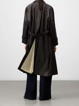 Gabardina larga color marrón con acabado efecto encerado, cuello con solapas anchas, cierre cruzado y bolsillos laterales. Incluye cinturón ajustable y detalles de trabillas en los puños.