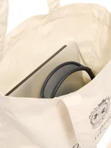 Bolso tipo tote de lona color beige, con diseño de logo Under Armour Athletics estampado en el frente. Cuenta con un amplio compartimento principal y correas dobles para llevar al hombro.