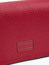 Cartera bandolera roja de poliuretano con correa ajustable, cierre con solapa y logo engomado de Tommy Jeans.