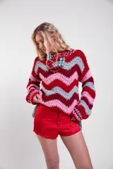 Sweater tejido a crochet de lana merino con diseño de rayas en zigzag de colores, cuello redondo, mangas largas amplias y calce holgado.