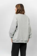 Buzo oversize de cuello redondo, confeccionado en algodón suave con interior frizado. Presenta un diseño de líneas simples, corte relajado y mangas largas con puños ajustados.