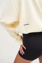 Buzo corto oversize color marfil con elástico en el ruedo inferior y bordado en la espalda.