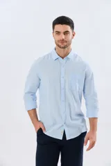 Camisa de lino de manga larga en color beige, con cuello camisero, cierre frontal de botones y un bolsillo ojal en el pecho.
