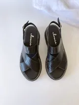 Sandalias negras de cuero con tiras cruzadas, plataforma track y hebilla lateral.