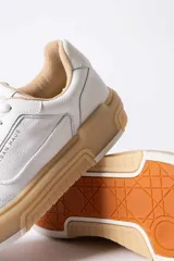 Championes urbanos Urban Haus modelo Alvaro, de cuero blanco con suela de plataforma color caramelo. Presentan cordones al tono y logo de la marca grabado en el lateral y la lengüeta.