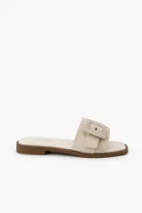 Sandalias planas de color beige claro con capellada ancha y hebilla cuadrada decorativa forrada en material trenzado.