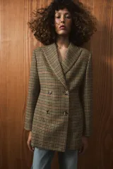 Blazer de corte entallado con estampado de cuadros, cuello solapa y cierre frontal cruzado con botones. Presenta mangas largas con detalle de abertura y botones en los puños, y forro interior a contraste.