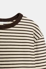 Camiseta de manga larga con diseño de rayas horizontales en color crudo y marrón oscuro. Presenta cuello redondo en contraste y corte regular con bajo recto.