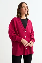 Cardigan de punto color fucsia, con cuello en V, cierre frontal con botones y bolsillos laterales. Presenta un diseño holgado con mangas largas y puños acanalados.