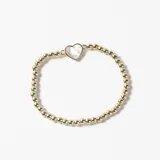 Pulsera elástica compuesta por pequeñas esferas metálicas doradas y un dije central en forma de corazón con incrustación de nácar.