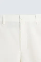Bermuda de algodón color blanco, de corte relajado, con cintura elástica, bolsillos frontales y bolsillos traseros de plastrón. Cierre frontal con cremallera y botón.