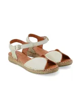 Sandalia plana tipo alpargata de cuero napa color crema, con tira frontal envolvente, talón cerrado y pulsera al tobillo con hebilla metálica de ajuste. Cuenta con suela revestida en yute trenzado.