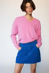 Falda mini de pana azul, con diseño de cinco bolsillos, cierre frontal con cremallera y botón.