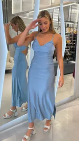 Vestido midi celeste metalizado, con diseño fruncido en el cuerpo, escote en V con tirantes finos regulables y espalda descubierta con tiras cruzadas.