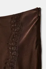 Falda midi de tiro alto confeccionada en tejido satinado color marrón. Presenta un diseño evasé con aplicación de encaje en el lateral y el bajo, y cierre lateral con cremallera oculta.