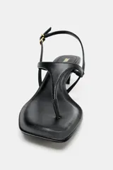 Sandalia de tacón kitten fino, color negro, con diseño de tiras tipo tanga y punta cuadrada. Cuenta con una tira trasera ajustable mediante hebilla metálica.