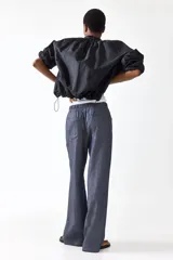 Pantalón recto de corte holgado con cintura elástica de tiro alto y cordón ajustable. Presenta bolsillos delanteros y traseros abiertos.