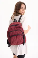 Mochila de nylon color bordó, con diseño acolchado, compartimento principal con cierre, bolsillos frontales con cierre y correas ajustables negras.