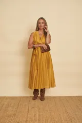 Vestido midi sin mangas de color mostaza, con escote en V cruzado y un lazo ajustable en la cintura.