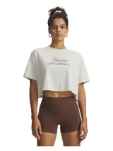 Remera crop top de Under Armour color blanco, con cuello redondo acanalado y estampa frontal con el logo de la marca en tipografía cursiva color marrón.