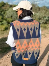 Chaleco tejido sin mangas con escote en V, presenta un diseño geométrico de rombos en tonos azul marino, naranja y gris. Confeccionado en tejido de punto liviano, posee terminaciones acanaladas en el cuello, sisas y ruedo.