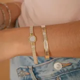 Brazalete rígido de diseño minimalista, elaborado en una combinación de plata y oro, con tres circonias engastadas en el centro.