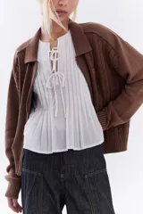 Blusa blanca sin mangas de algodón, con diseño de tablas frontales y escote con lazos para atar.