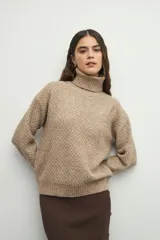 Polera de cuello alto con textura tramada, manga larga con puños acanalados y diseño holgado.