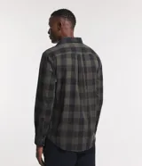 Camisa de hombre de manga larga, confeccionada en franela de algodón, con cuello inglés y abotonadura frontal. Presenta un estampado de cuadros grandes en tonos verde oliva y negro.