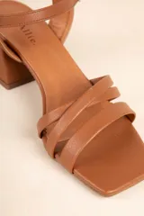 Sandalias de cuero sintético color marrón, con tiras cruzadas y hebilla metálica ajustable. Cuentan con un taco ancho de 6cm de alto.