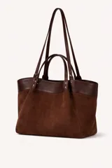 Cartera tipo tote bag de diseño estructurado, confeccionada en una combinación de gamuza marrón en el cuerpo principal y cuero liso en la parte superior y asas. Cuenta con doble juego de asas, unas cortas para llevar en la mano y otras largas para colgar al hombro, con detalles de remaches metálicos.