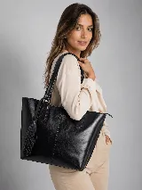 Cartera tipo tote bag de cuero genuino color negro, con diseño estructurado, costuras verticales decorativas, asas de hombro y detalle de borla colgante con flecos.