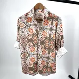 Camisa de manga larga con cuello italiano, color marrón con estampado de flores y cachemir en tonos naranja, rosa y blanco.