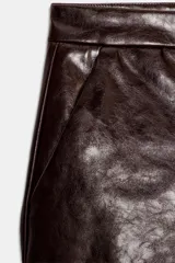 Shorts de tiro bajo confeccionados en material sintético con acabado efecto piel, cuentan con bolsillos delanteros y cierre frontal con cremallera y gancho metálico.