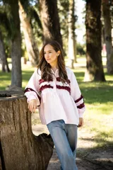 Camisa de lino color rosa claro con corte holgado, cuello camisero y mangas largas. Presenta detalles de volados horizontales en color bordó en el frente y en las mangas.