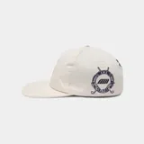 Gorra color beige con visera plana y parche bordado en el frente con escudo y la inscripción 'GOLF'.