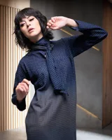 Vestido azul con estampado a cuadros, cuello con lazo y corte recto holgado con aberturas laterales.