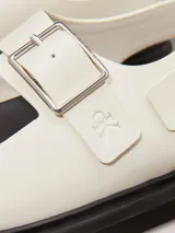 Sandalias de piel lisa color blanco con suela de goma negra, tiras anchas con hebillas metálicas ajustables y plantilla moldeada.