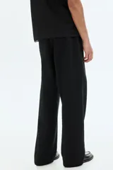 Pantalón de jogging negro de felpa pesada, corte holgado con cintura elástica ajustable mediante cordón y bolsillos laterales.