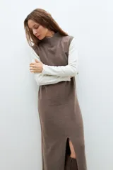Vestido midi tejido color chocolate, de corte recto, cuello alto y sin mangas. Presenta un tajo frontal.