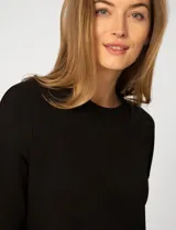 Buzo de punto color rosa, con cuello redondo y detalle de tejido crochet en el escote. Presenta mangas largas y un corte clásico con caída suave.