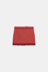 Minifalda de tiro medio confeccionada en tejido de tweed rojo, con diseño estructurado y terminaciones deshilachadas en el borde inferior. Cuenta con cierre en la espalda con cremallera oculta en costura.