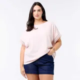 Camiseta rosada con cuello redondo y mangas cortas holgadas que presentan detalles de bordado y macramé.