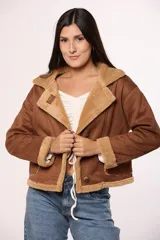 Campera tipo gamulán de gamuza color marrón con interior y detalles de corderito en color beige. Presenta cierre frontal con botones, cuello solapa y bolsillos cuadrados frontales.