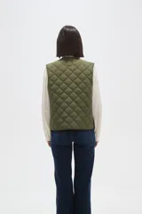 Chaleco acolchado de color negro con diseño de rombos, cierre frontal con botones metálicos a presión y dos bolsillos delanteros aplicados.