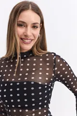 Body de manga larga confeccionado en tejido mesh transparente con estampado de lunares blancos sobre fondo negro. Presenta cuello alto y un diseño ajustado al cuerpo.