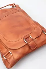 Morral de cuero liso negro, con correa ajustable larga para llevar al hombro o cruzado. Presenta un bolsillo frontal con solapa y cierre de hebilla decorativa.