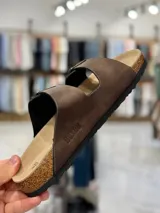 Sandalias de dos tiras negras con hebillas metálicas ajustables, plantilla anatómica y suela plana.